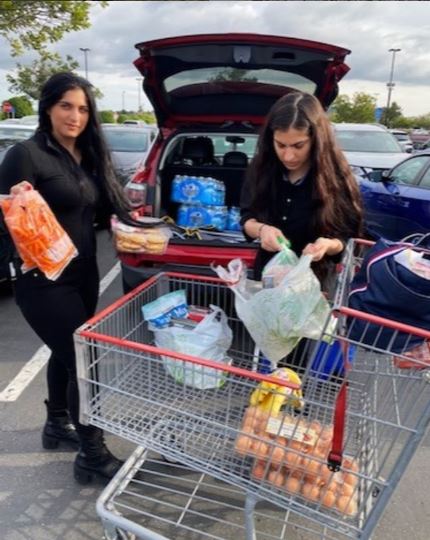 Two female students loading groceries from a cart into their car